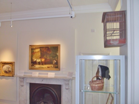 A birdcage overlooks its corresponding painting